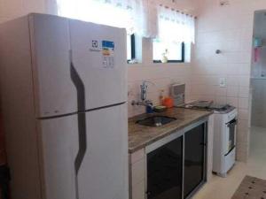La cuisine est équipée d'un réfrigérateur blanc et d'un évier. dans l'établissement Ap. portaria 24 hs/área de lazer/Itagua, à Ubatuba