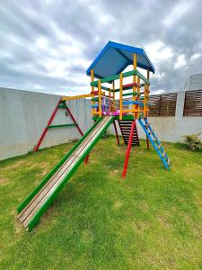 un parque infantil con un tobogán en el césped en POUSADA ROSA e POESIA, en Praia do Rosa