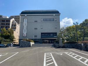 um parque de estacionamento vazio em frente a um edifício em パインツリー em Matsuyama