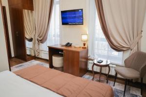 ビシュケクにあるRivieraのベッド、デスク、テレビが備わるホテルルームです。