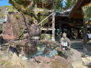 una estatua de una persona sentada en una roca en パインツリー, en Matsuyama