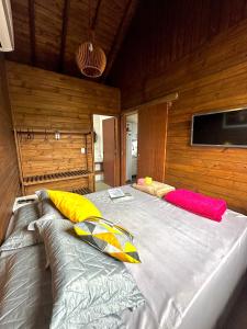 a bedroom with two beds in a wooden wall at POUSADA ROSA e POESIA in Praia do Rosa