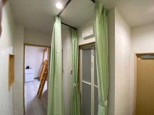 um quarto com cortinas verdes e uma porta em パインツリー em Matsuyama
