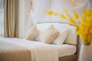 a white bed with pillows and a vase of flowers at Lavender Apartment Branch in Guangzhou