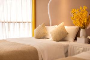 a white bed with white pillows and a vase of flowers at Lavender Apartment Branch in Guangzhou