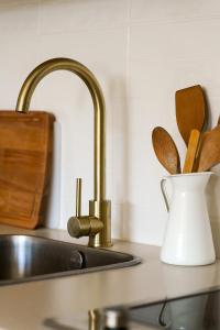 a kitchen counter with a sink and a vase with wooden utensils at Estúdio do Largo - Vilamoura in Vilamoura