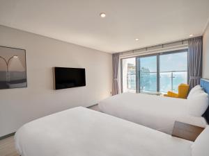 um quarto de hotel com duas camas e uma janela em Y Collection by UH FLAT Haeundae beach em Busan