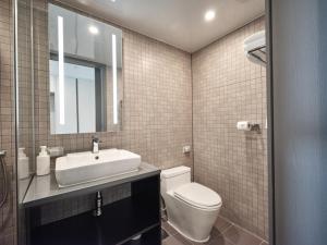 La salle de bains est pourvue de toilettes, d'un lavabo et d'un miroir. dans l'établissement Y Collection by UH FLAT Haeundae beach, à Busan