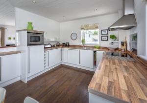 a kitchen with white cabinets and a wooden floor at 4 Ynys Fawr in Abersoch