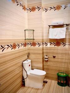a bathroom with a toilet and flowers on the wall at HOTEL MINH LÂM 2 in Pleiku +23 photos