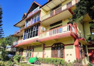 Hotel Mandal Ghang Arunachal Pradesh في Bhalukpung: مبنى كبير فيه بلكونات جنبه