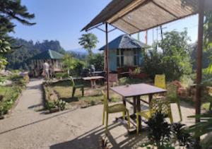 Hotel Mandal Ghang Arunachal Pradesh في Bhalukpung: فناء مع طاولة وكراسي ومنزل