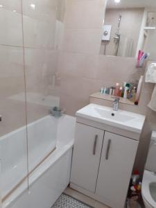 a white bathroom with a sink and a shower at Celebrity Home in Woolwich