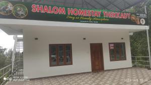 un bâtiment avec deux portes et un panneau sur celui-ci dans l'établissement Shalom Homestay Thekkady, à Thekkady