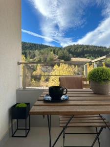 einen Holztisch mit einer Kaffeetasse auf dem Balkon in der Unterkunft Арт Мезонет Salem in Welingrad