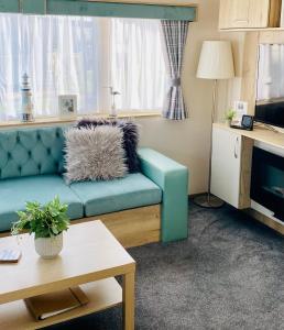 - un salon avec un canapé bleu et une table dans l'établissement The Wardens Escape - Tattershall Lakes Country Park, à Tattershall