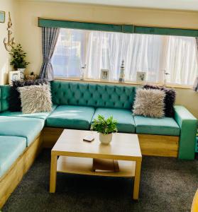 a living room with a green couch and a table at The Wardens Escape - Tattershall Lakes Country Park in Tattershall