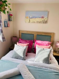 タターズホールにあるThe Wardens Escape - Tattershall Lakes Country Parkのベッドルーム1室(ピンクとブルーの枕が備わるベッド1台付)