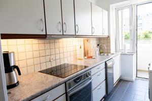 una cocina con armarios blancos y fregadero en Stefania en Aalborg