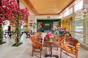 a dining room with tables and chairs and flowers at Papa Kana Farm Mitra RedDoorz At Pacet Mojokerto in Mojokerto