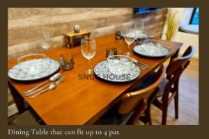 a wooden table with plates and wine glasses on it at Romantic Log Cabin 3 - in the Heart of KL city (walk to KL Tower/KLCC/Bukit Bintang) in Kuala Lumpur