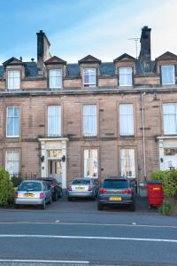 a large brick building with cars parked in front of it at The Ben Doran Guest House in Edinburgh