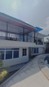a large white building with a balcony and a pool at Villa Dalia Puncak P2-12 in Tjiandjur