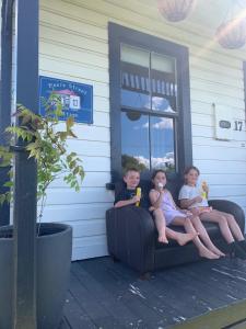 two children sitting on a couch outside of a house at Moore St Cottage in Ohakune