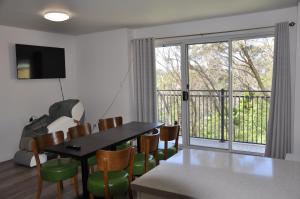 a dining room with a table and chairs and a balcony at Modern 3-bedroom Katoomba townhouse (nature view) in Katoomba