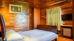 a bedroom with a wooden wall with a bed and a television at KTM Resort Batam in Sekupang