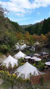 Une bande de tentes blanches dans un champ planté d'arbres dans l'établissement fabula glamping, à Kimitsu