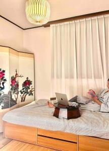 un homme dormant sur un lit avec un ordinateur portable dans l'établissement Seokchon Byeolchae, à Séoul