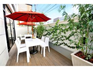 a table and chairs with a red umbrella on a balcony at Grand Park Hotel Panex Hachinohe / Vacation STAY 77776 in Hachinohe