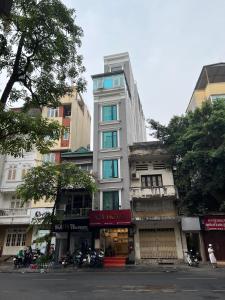 un edificio alto de color blanco con ventanas azules en una calle en A25 Hotel - 88 Nguyễn Khuyến en Hanoi