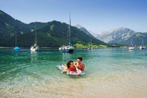 a man and a child in the water on a beach at Apartment in Achenkirch with a garden in Achensee