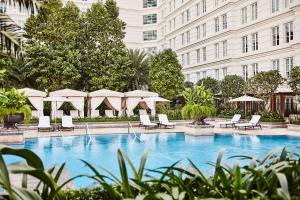 a swimming pool with chairs and umbrellas next to a building at Park Hyatt Saigon in Ho Chi Minh City