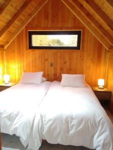 1 dormitorio con 2 camas blancas y ventana en Tiny House Camino a Cascadas, Lago Llanquihue en Puerto Octay
