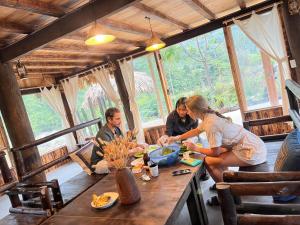 um grupo de pessoas sentadas numa mesa numa cabana em Lao Chải riverside stay&coffee em Sapa