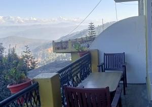a table and chairs on a balcony with a view at Himalaya Mount View Resort Uttarakhand in Kausani