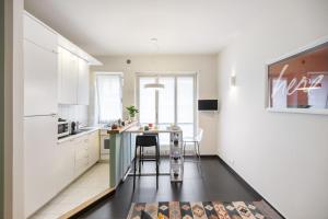 cocina con armarios blancos, mesa y sillas en Here apartment en Turín