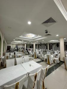 um salão de banquetes com mesas e cadeiras brancas em BUKHARA GRAND HOTEL em Bukhara