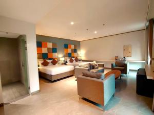 a hotel room with a bed and a couch and chairs at Yes Hotel San Ildefonso Bulacan in Buliran