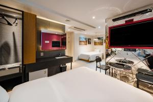 a hotel room with a bed and a large screen tv at H-AVENUE Hotel Yeoksam in Seoul