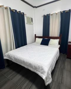 uma cama num quarto com cortinas azuis em Charlotte's Vacation Home Busuanga Palawan 