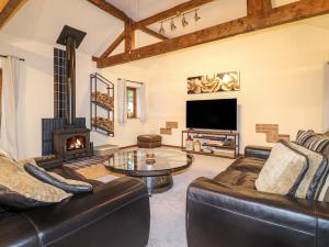 uma sala de estar com mobiliário de couro e uma lareira em Wheatlow Brooks Barn em Stafford