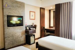 a hotel room with a bed and a flat screen tv at Crown Victoria Hotel Tulungagung in Tulungagung