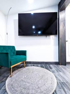 a living room with a green chair and a large tv at Casita Hosum: Modern WFH Garden Suite w/ Gazebo Outdoor Kitchen & BBQ in San Jose