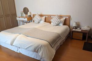 een slaapkamer met een groot bed met witte lakens en kussens bij Roomy 4BR Home Sleeps 9／ShinOsaka／Large Groups in Osaka