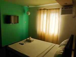 Un dormitorio con una cama con paredes verdes y una ventana en Villa Rosita Hotel, en Naga