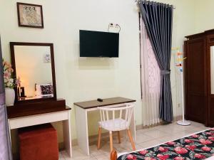 Habitación con escritorio, espejo y TV. en Just 11 Boutique Syariah Mitra RedDoorz near UGM Yogyakarta, en Kejayan